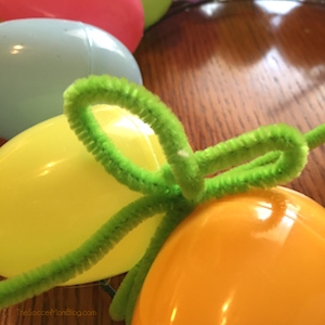 making a pipe cleaner bow on an egg wreath for Easter