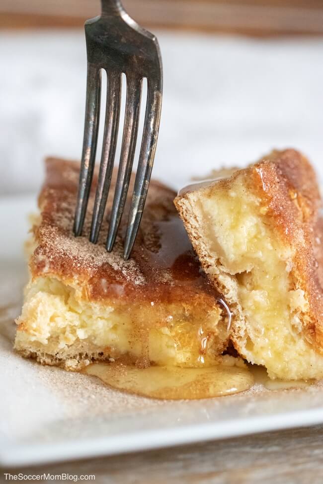 sopapilla cheesecake bars with a fork and drizzled with honey.