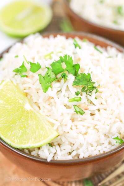 close up of a bowl of coconut rice with lime and fresh herbs