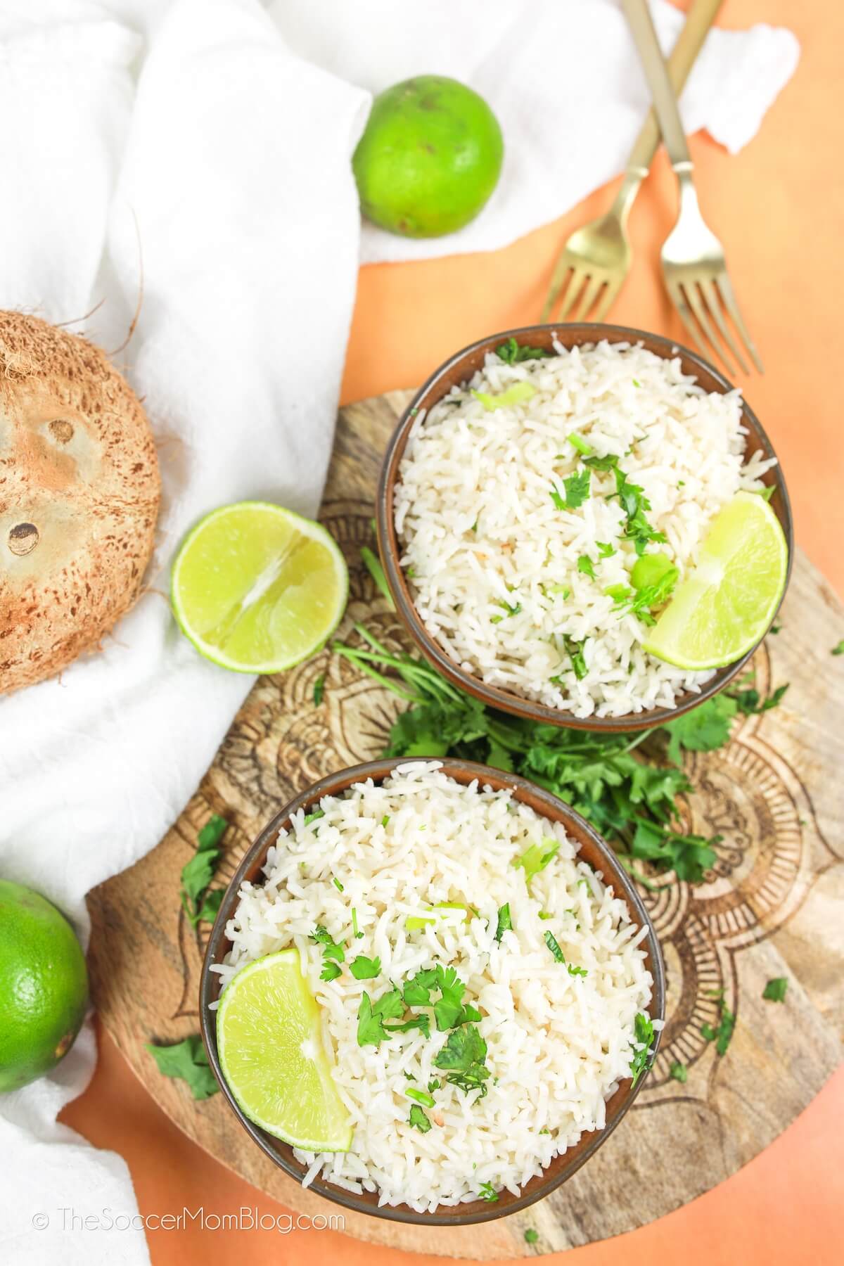 two bowls of rice on counter, with limes and coconut