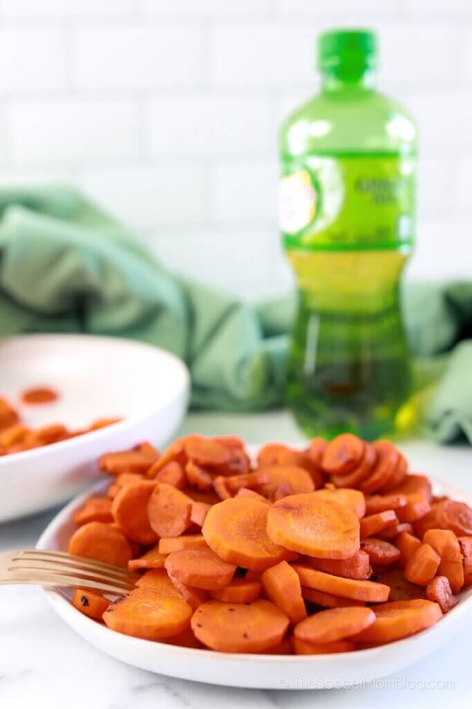 glazed carrots on a plate with bottle of ginger ale in background