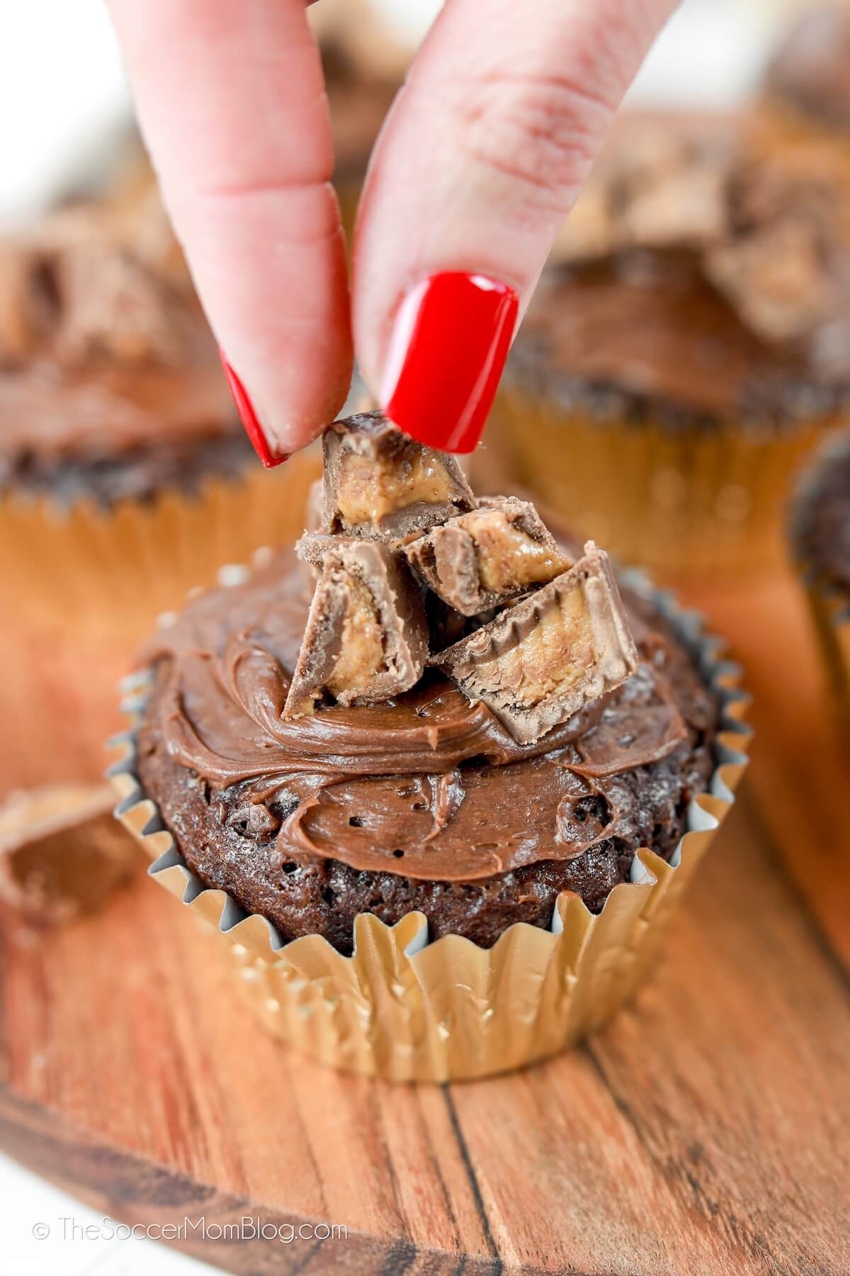 decorating a chocolate peanut butter cupcake with Reese's cups