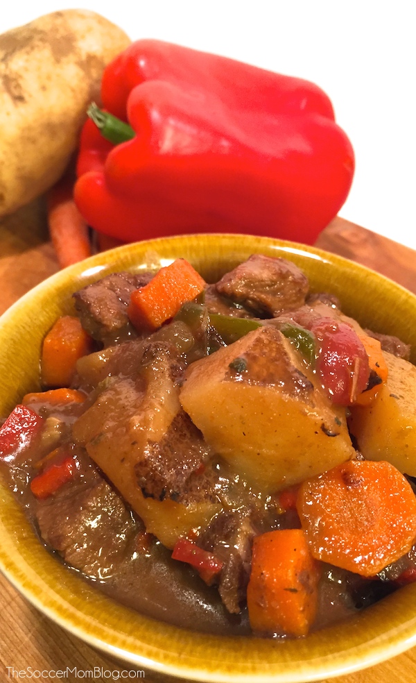 bowl of Mexican beef stew with pepper and potato in background