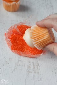 dipping orange cupcakes in sprinkles