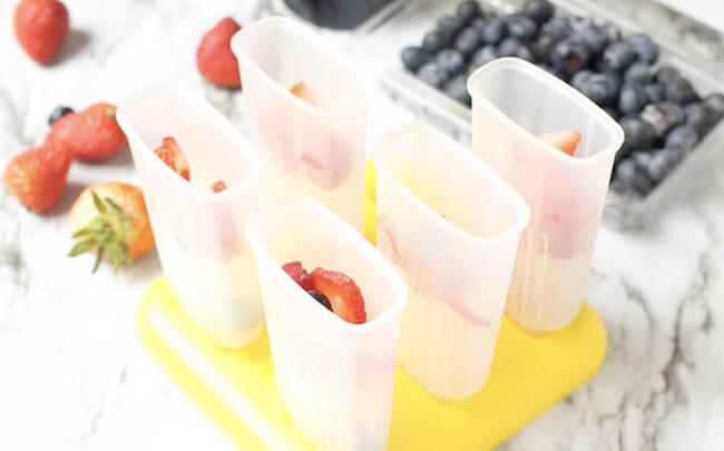 making sangria popsicles with fresh fruit in popsicle molds