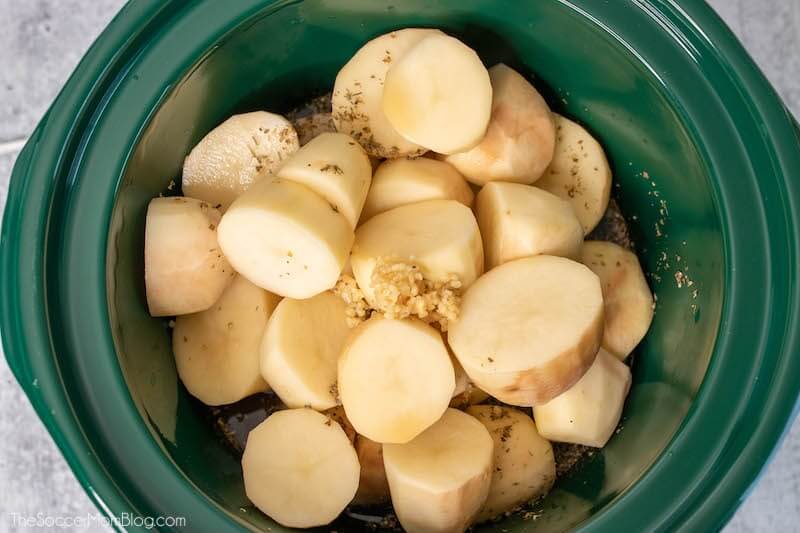 Chopped potatoes in crockpot with garlic and herbs