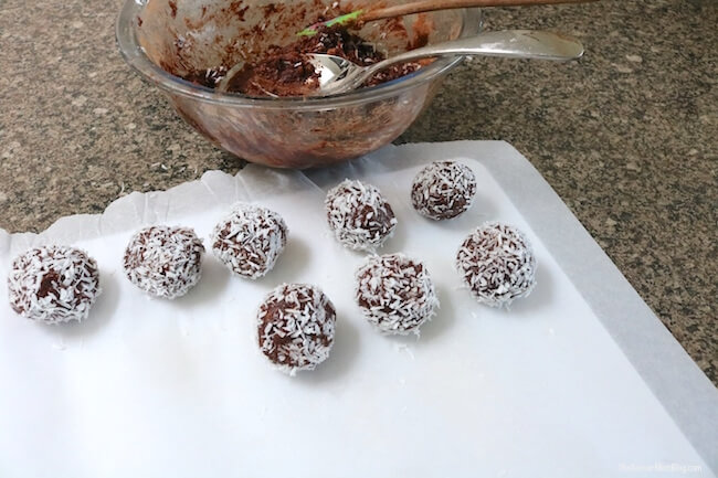 placing chocolate coconut protein balls on baking sheet