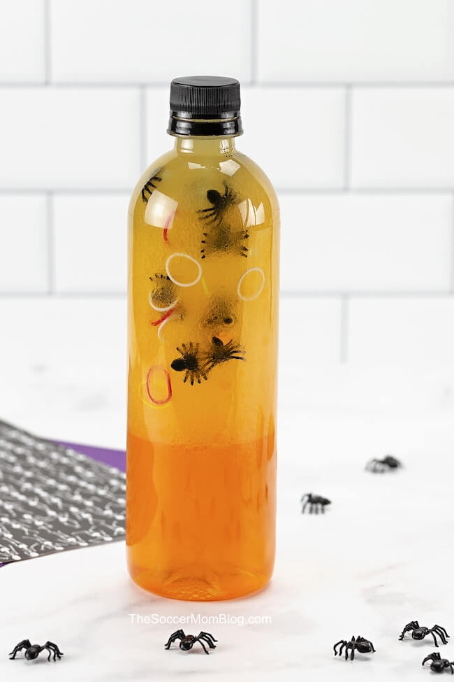 orange Halloween sensory bottle with plastic spiders inside