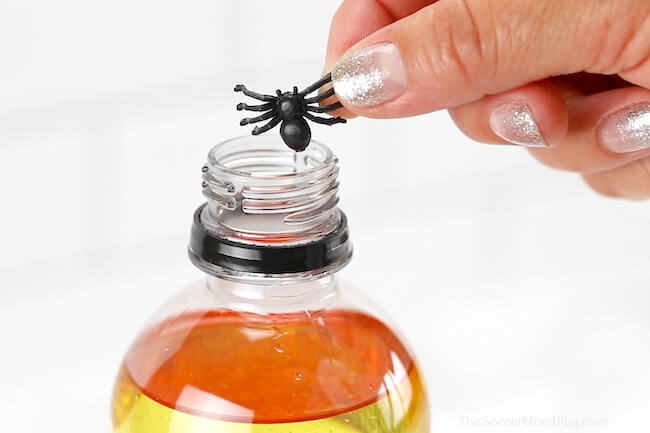 putting plastic spiders in a Halloween bottle craft