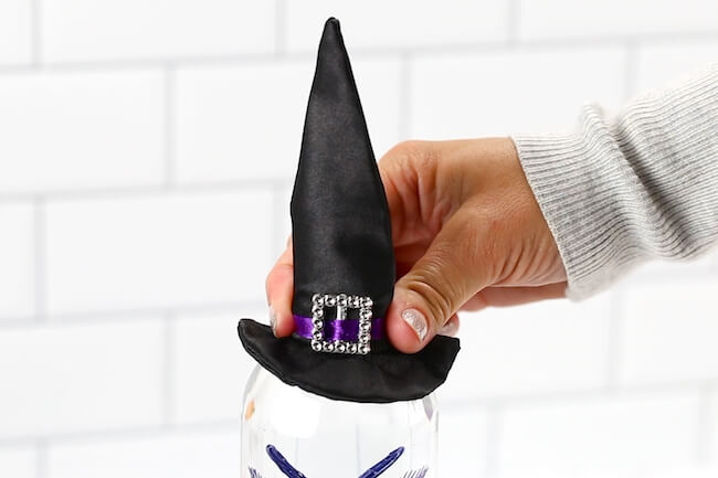 putting a mini witch hat on a water bottle