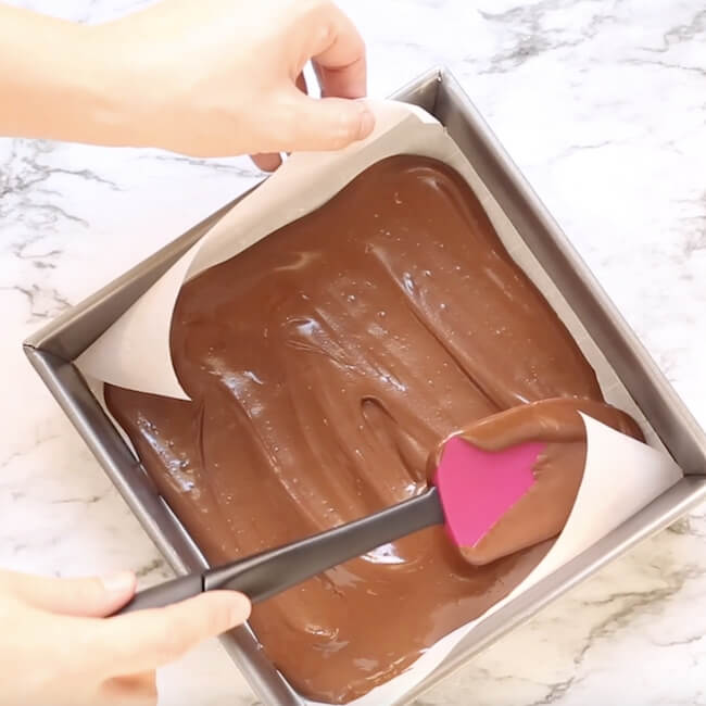 spreading melted chocolate into baking pan lined with parchment paper