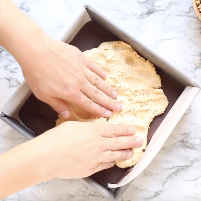 pressing nougat into baking pan on top of chocolate layer