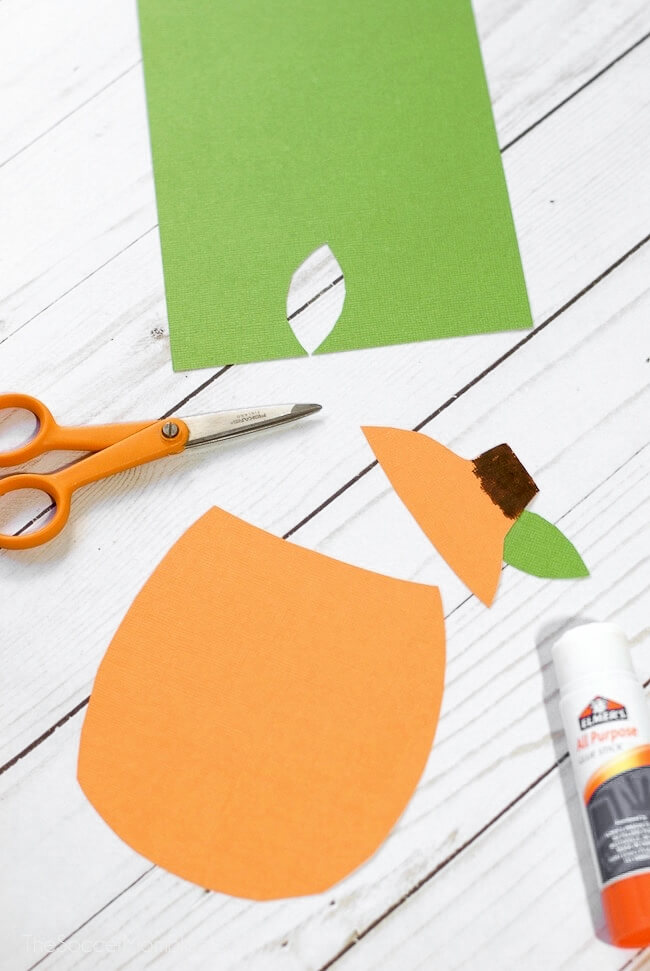 orange and green construction paper being crafted into a pumpkin