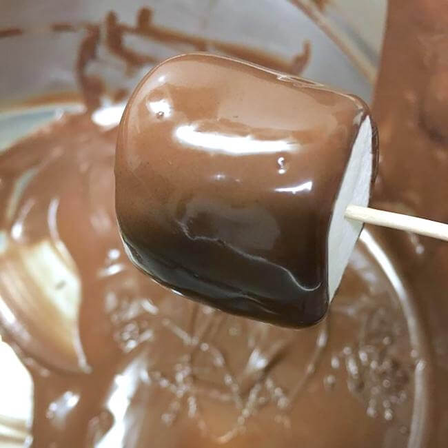 dipping marshmallow in melted chocolate