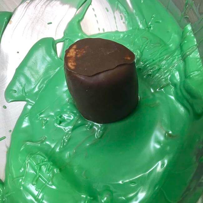 dipping marshmallow into melted green chocolate