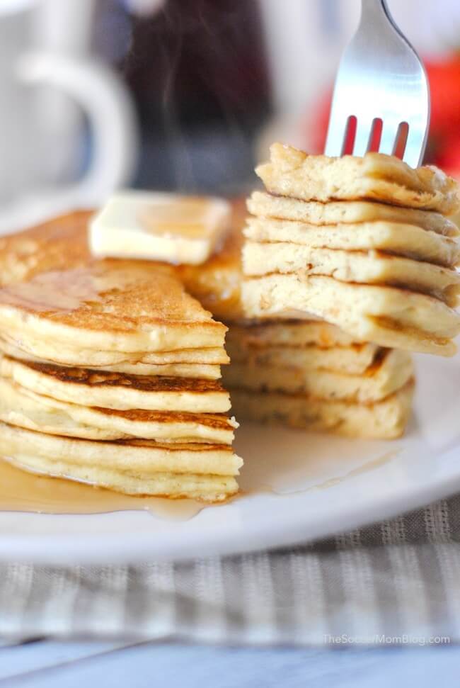steaming stack of pancakes and a fork with a bite 