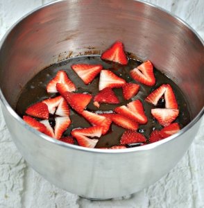 Strawberries in chocolate brownie batter in mixing bowl