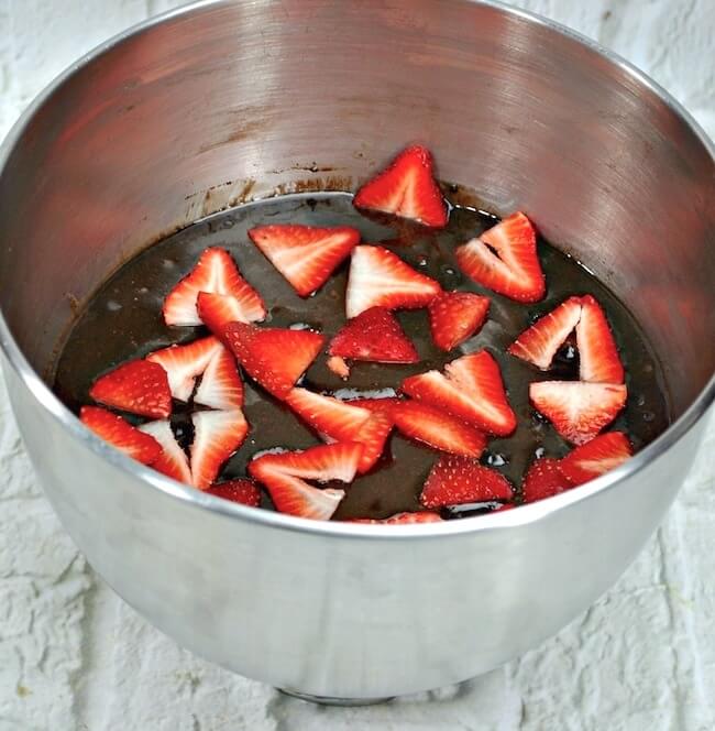 Stainless mixing bowl with brownie batter and strawberries