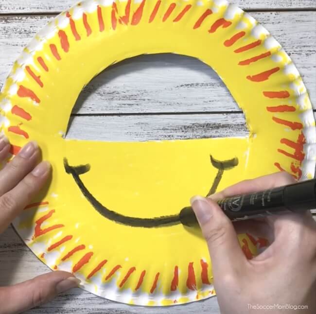 Drawing a smiley face on a paper plate