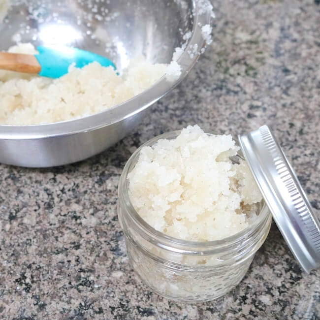 scooping homemade lip exfoliating scrub into mason jar