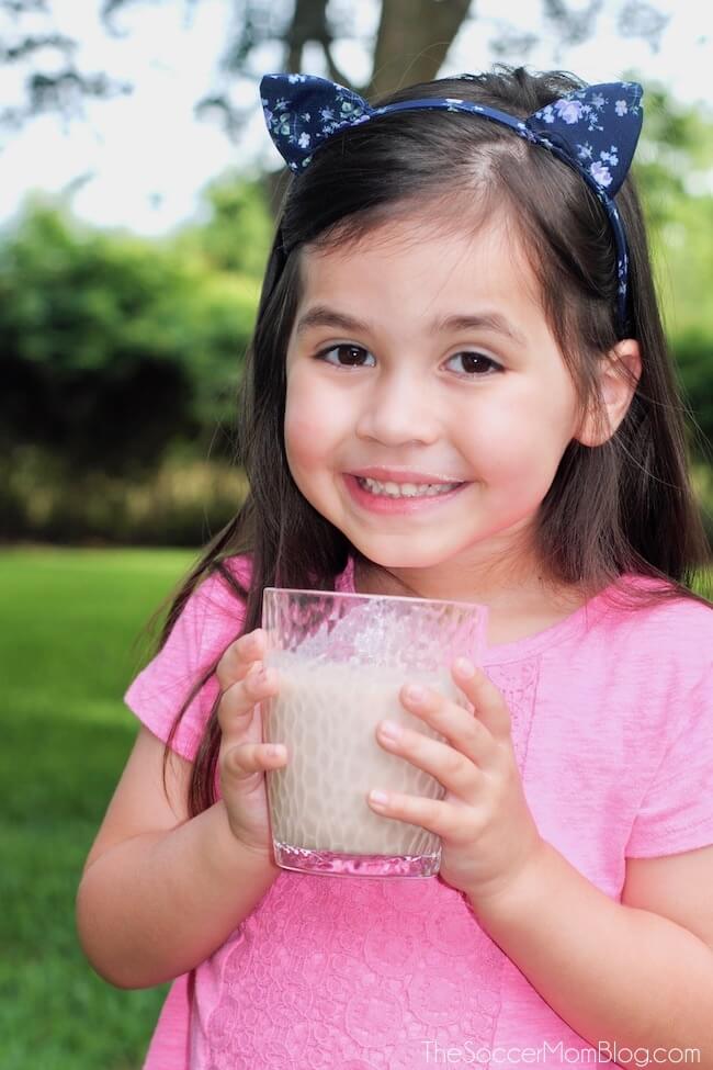 little girl smiling and drinking a protein shake