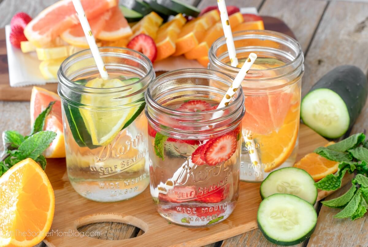3 mason jars of fruit infused water surrounded by fresh fruit.