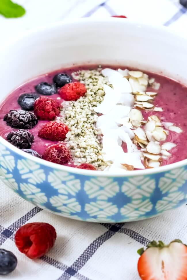a purple smoothie bowl topped with fresh berries