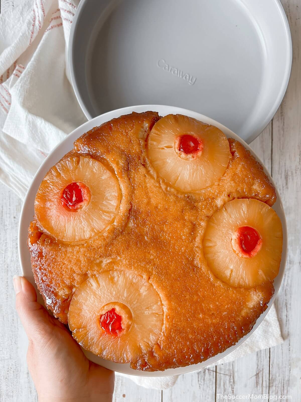 holding a pineapple upside down cake over cake pans