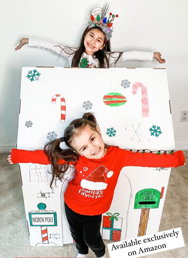 two girls with decorated homemade Christmas playhouse