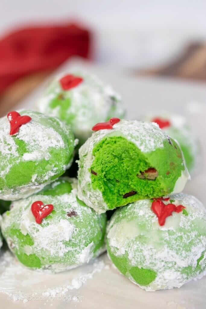 green snowball cookies with red heart decoration aka Grinch Cookies