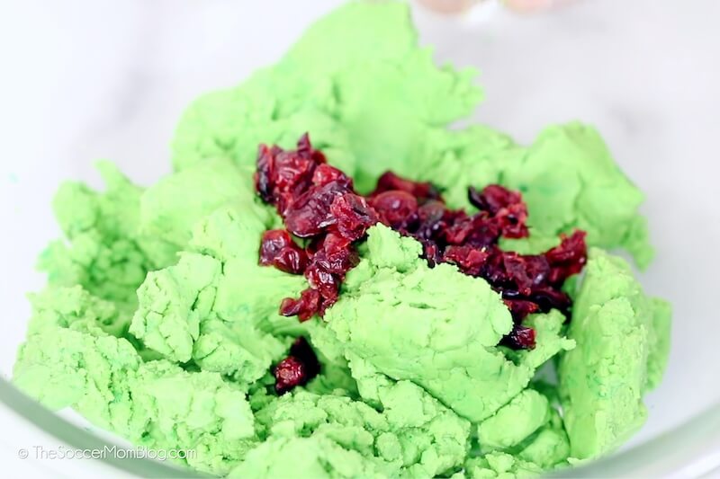 adding dried cranberries to green cookie dough