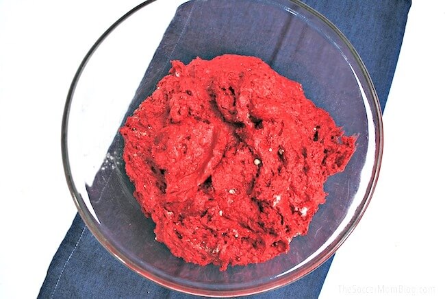 red velvet cinnamon roll dough in glass mixing bowl