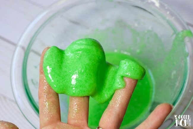 lime green jello slime dripping from fingers