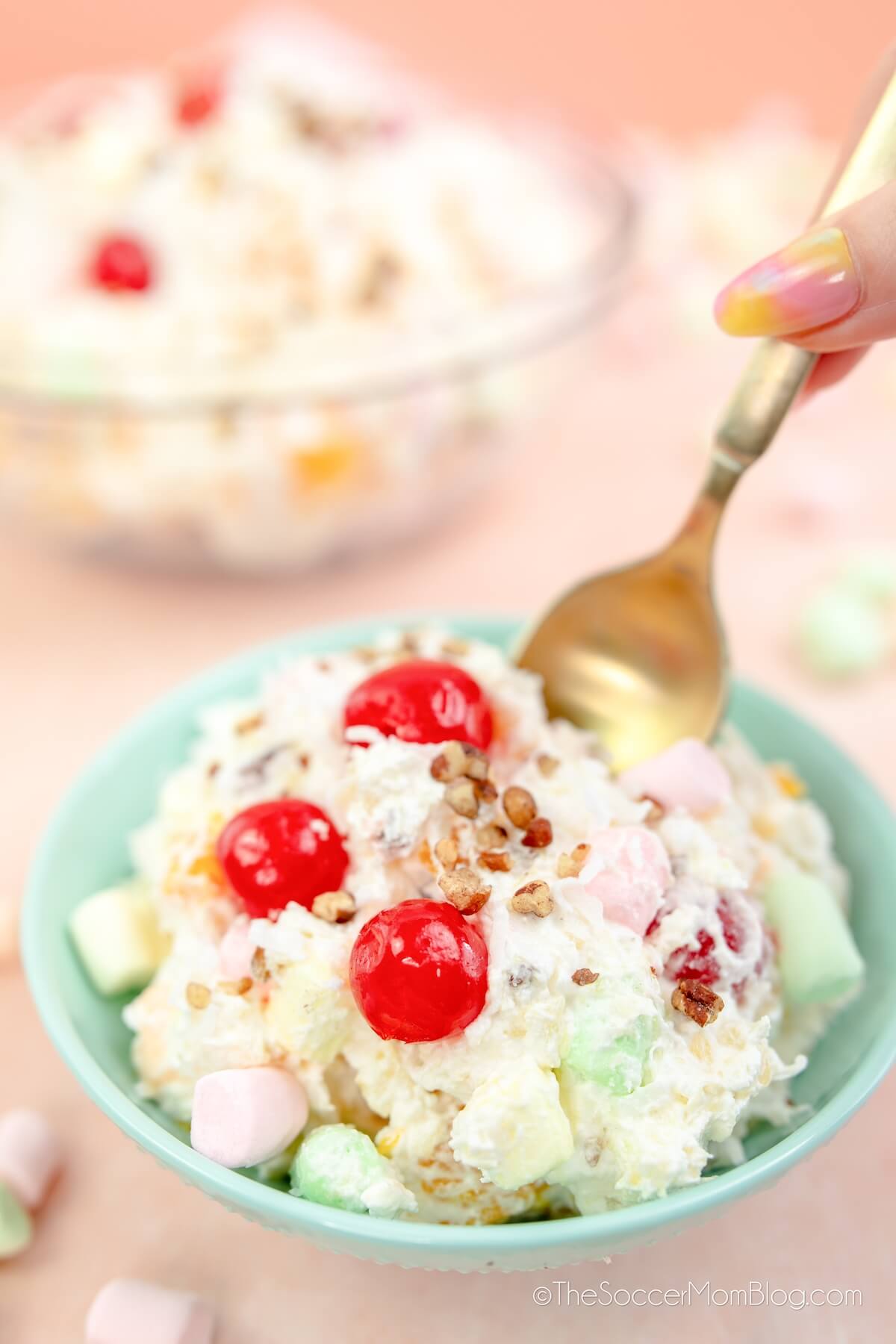 dipping a spoon into a bowl of marshmallow fruit salad