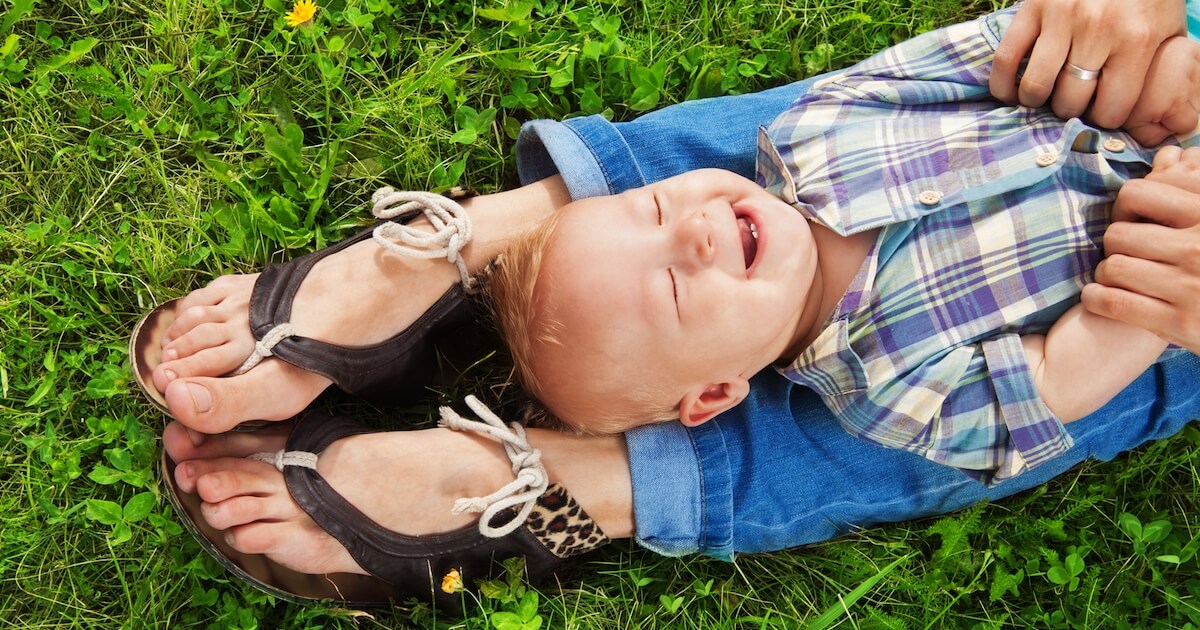 little boy laying on his mom's legs in the grass