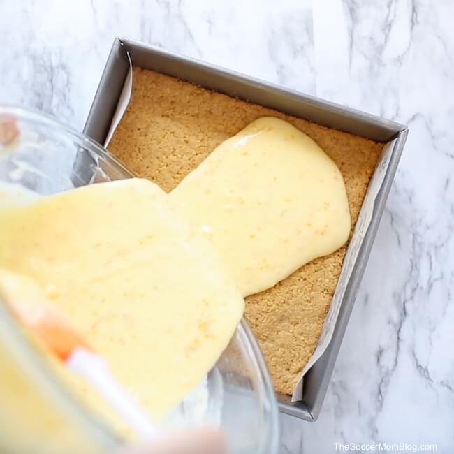 pouring orange cheesecake batter on crust