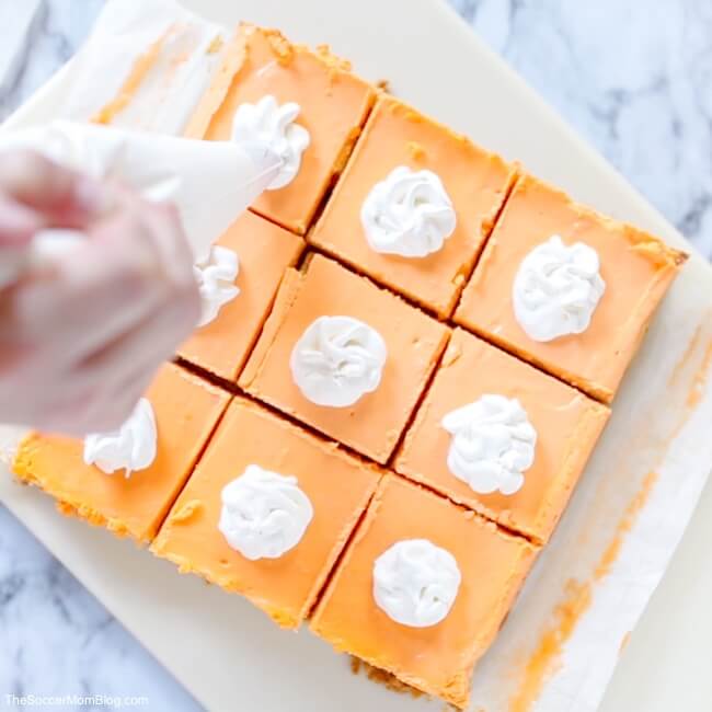 topping orange cheesecake bars with whipped cream