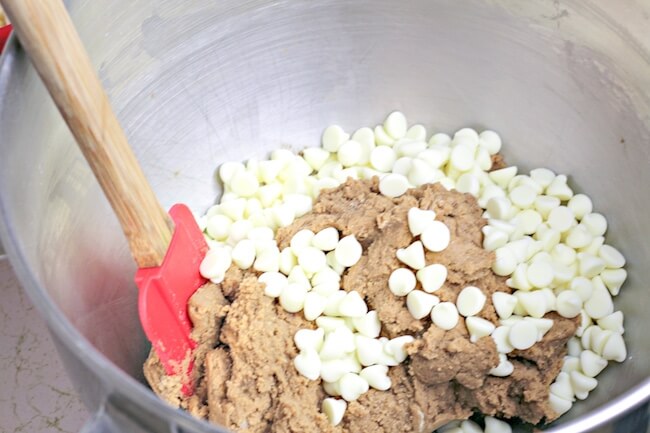 stirring white chocolate chips into root beer cookie batter