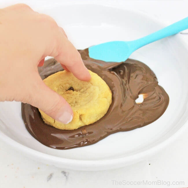 dipping thumbprint cookies into chocolate