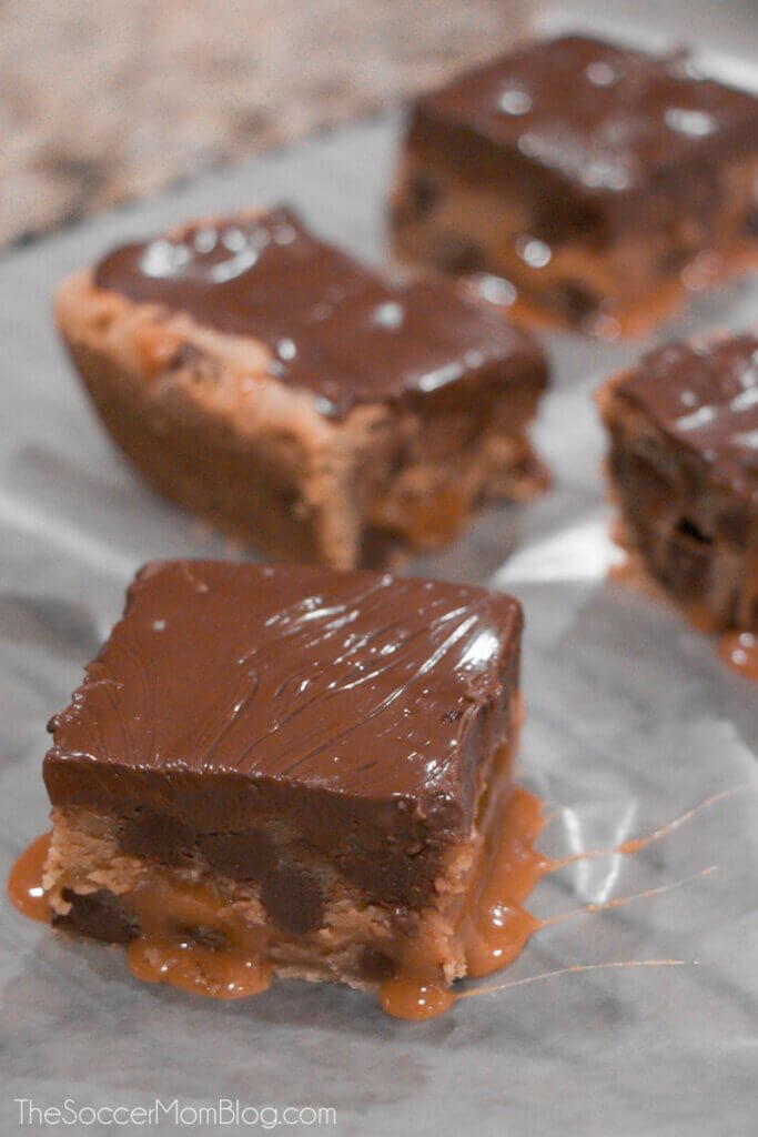 chocolate frosted caramel cookie bars on parchment paper