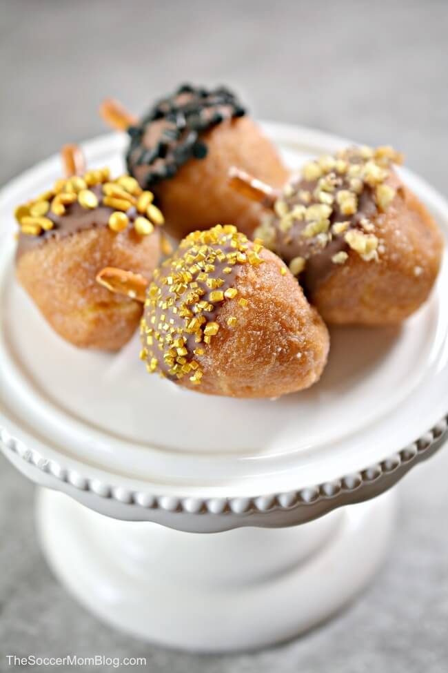 donut holes decorated to look like acorns, on a cake stand