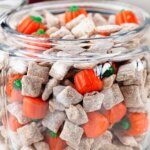 glass jar filled with fall snack mix and candy pumpkins