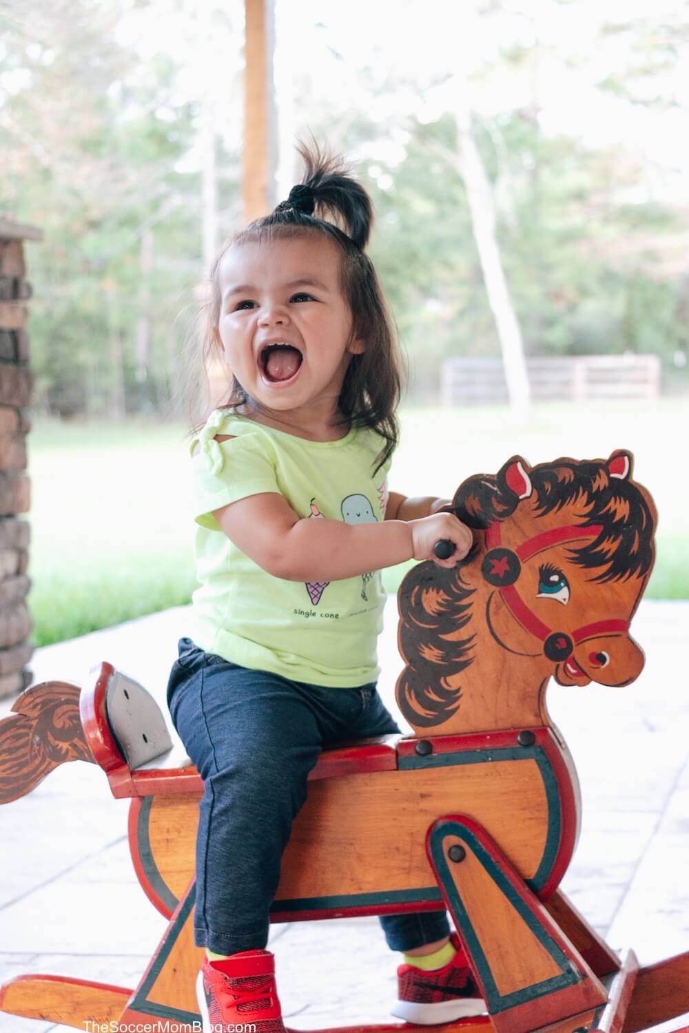 toddler girl on rocking horse with big smile