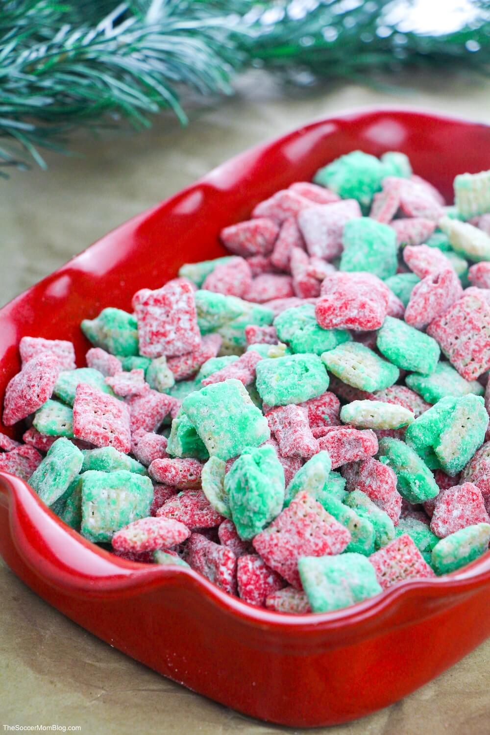 red dish with Christmas colored puppy chow snack mix