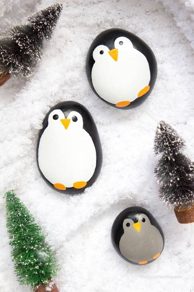 a family of penguin painted rocks in fake snow