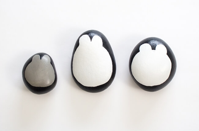three painted rocks with a black outline, like a penguin