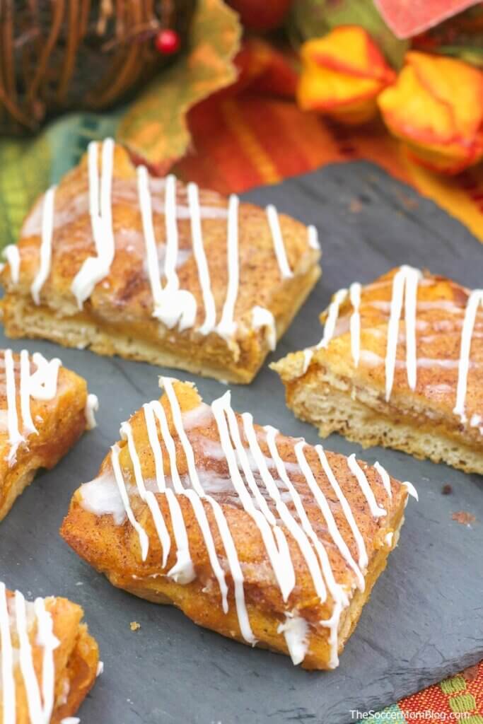 pumpkin cheesecake bars with cream cheese drizzle on a black serving plate