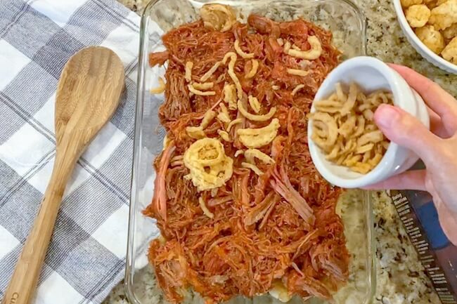 sprinkling fried onions on barbecue in casserole