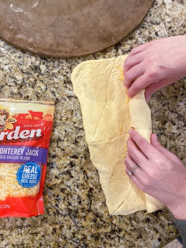 rolling up crescent dough to make a Christmas bread wreath