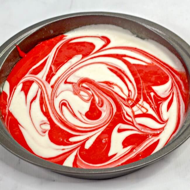 red and white swirled cake batter in pan